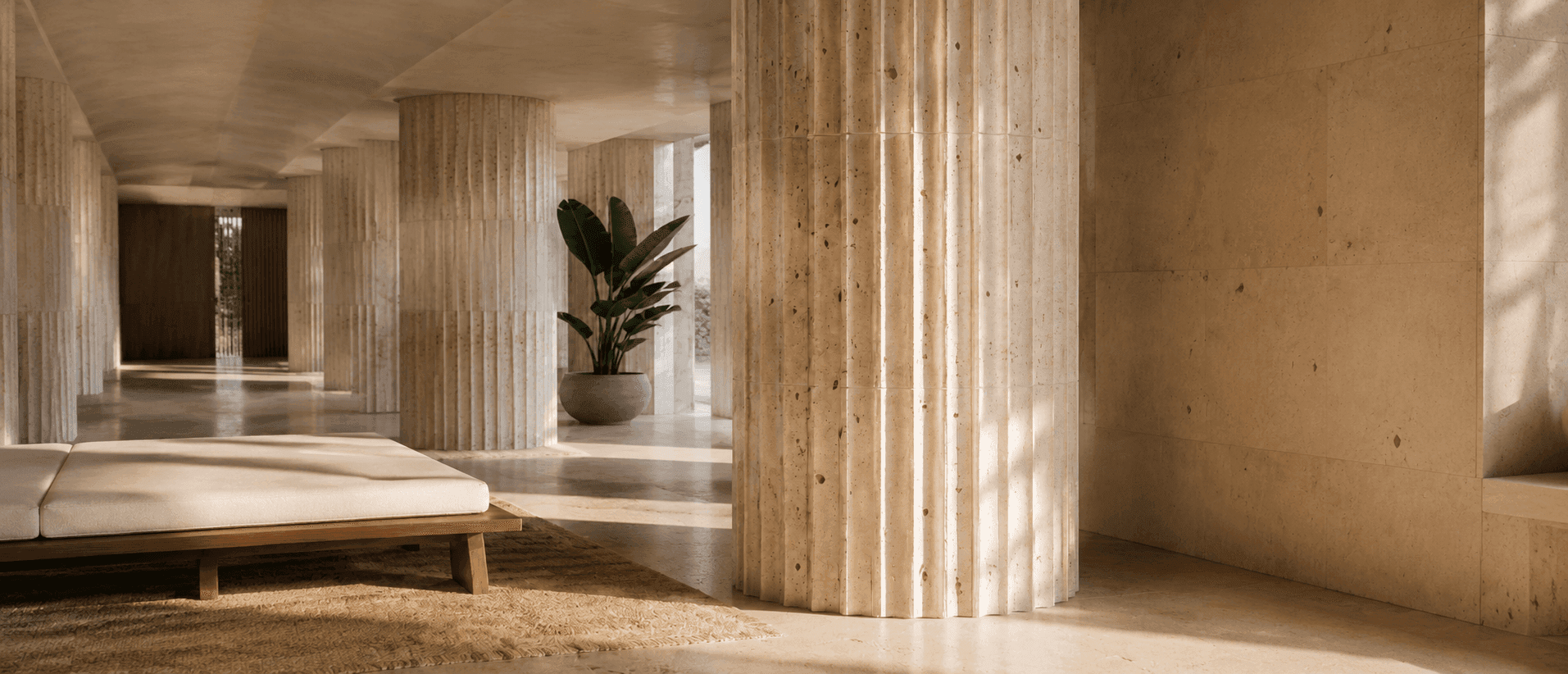 Flexible travertine cladding wrapping fluted columns in a sunlit gallery